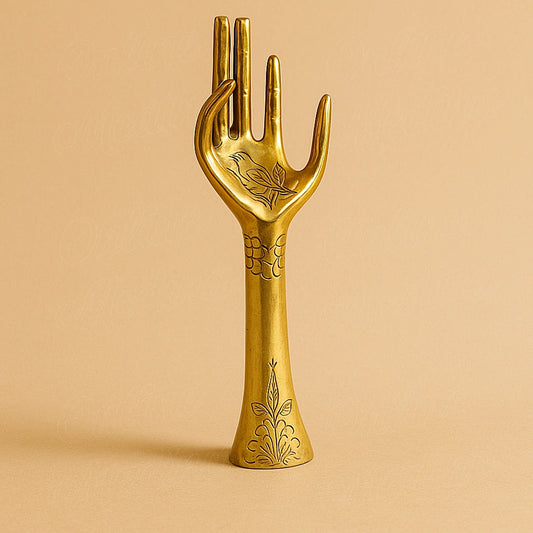 Handcrafted brass hand sculpture engraved with Moroccan floral motifs, displayed on a plain beige background