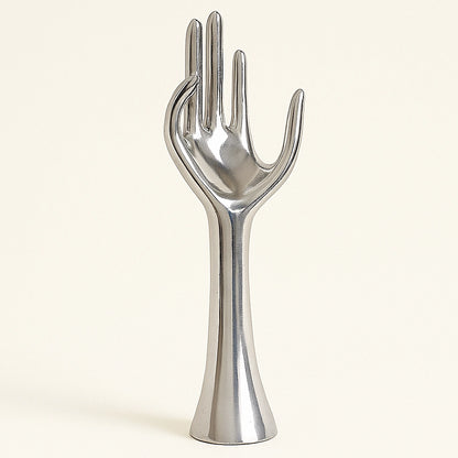 Polished aluminum hand sculpture with smooth surface and minimalist design, on a light neutral background