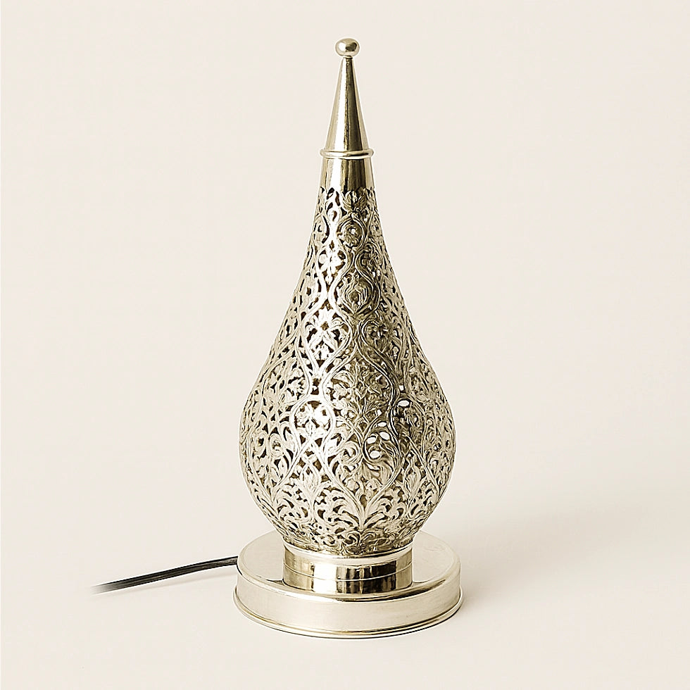 Silver Moroccan pierced metal lamp on a neutral background, teardrop-shaped with intricate filigree patterns and a polished base.