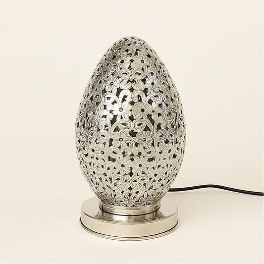 Silver Moroccan egg-shaped pierced lamp with floral patterns and polished base on a plain light background.