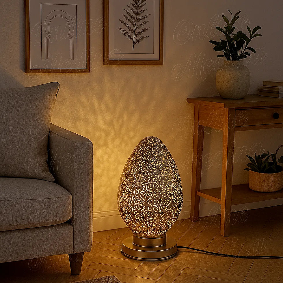 Lampe galet ajourée allumée près d’un canapé, projetant des motifs lumineux sur le mur