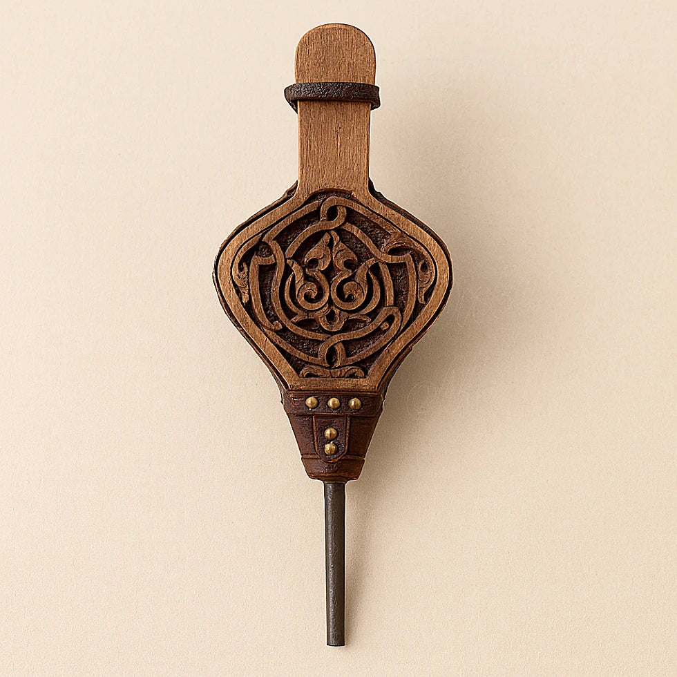 Front view of an artisanal Moroccan fireplace bellows, carved wood and leather details on beige background.