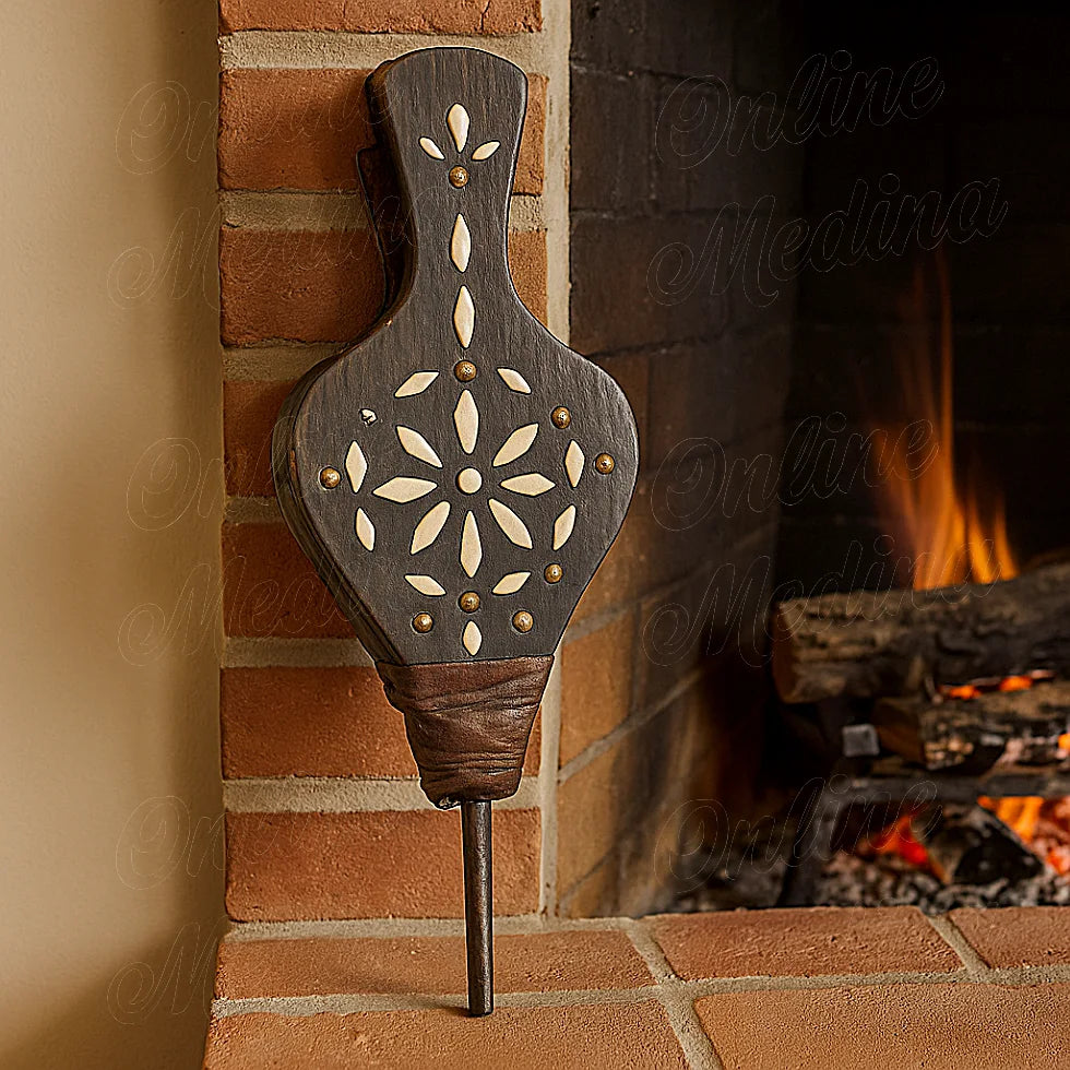 Moroccan handcrafted bellows with carved bone details, resting near a fireplace, warm and cozy atmosphere