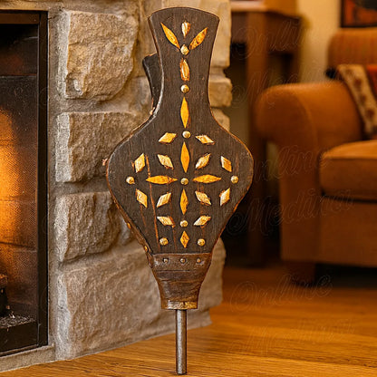 Moroccan artisanal bellows made of wood, leather, and bone, placed beside a stone fireplace in a cozy living room