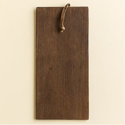 Back view of a handmade Berber wooden amulet showing the smooth dark brown cedar surface and the leather hanging loop.