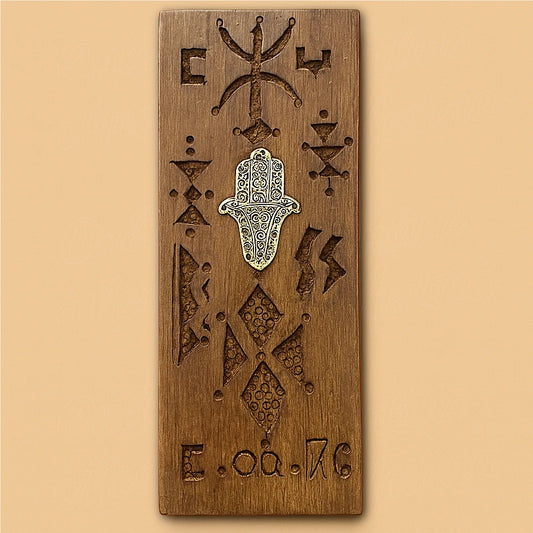 Front view of a handcrafted Moroccan cedar wood wall amulet with Amazigh carvings and a silver Fatima hand on a beige background.