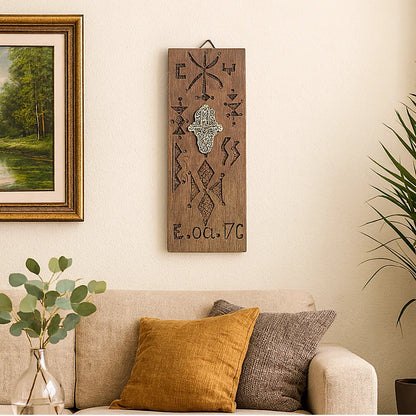 Handcrafted Moroccan cedar wood wall amulet with Amazigh carvings and silver Fatima hand hanging above a beige sofa in a modern living room.