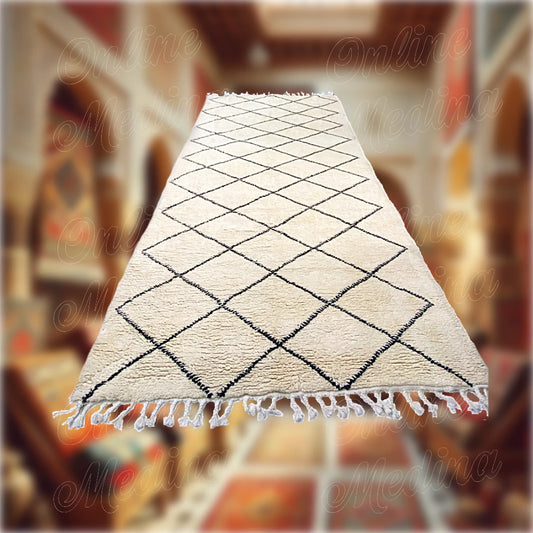 Handwoven Moroccan Beni Ouarain rug in white wool with black diamond patterns, displayed in a traditional carpet boutique.