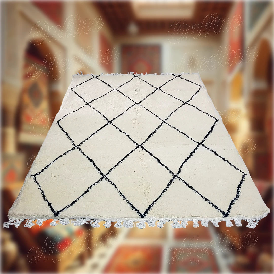 Tapis Beni Ouarain artisanal en laine blanche avec motifs en losanges noirs, fabriqué au Maroc, parfait pour une décoration intérieure authentique et moderne.