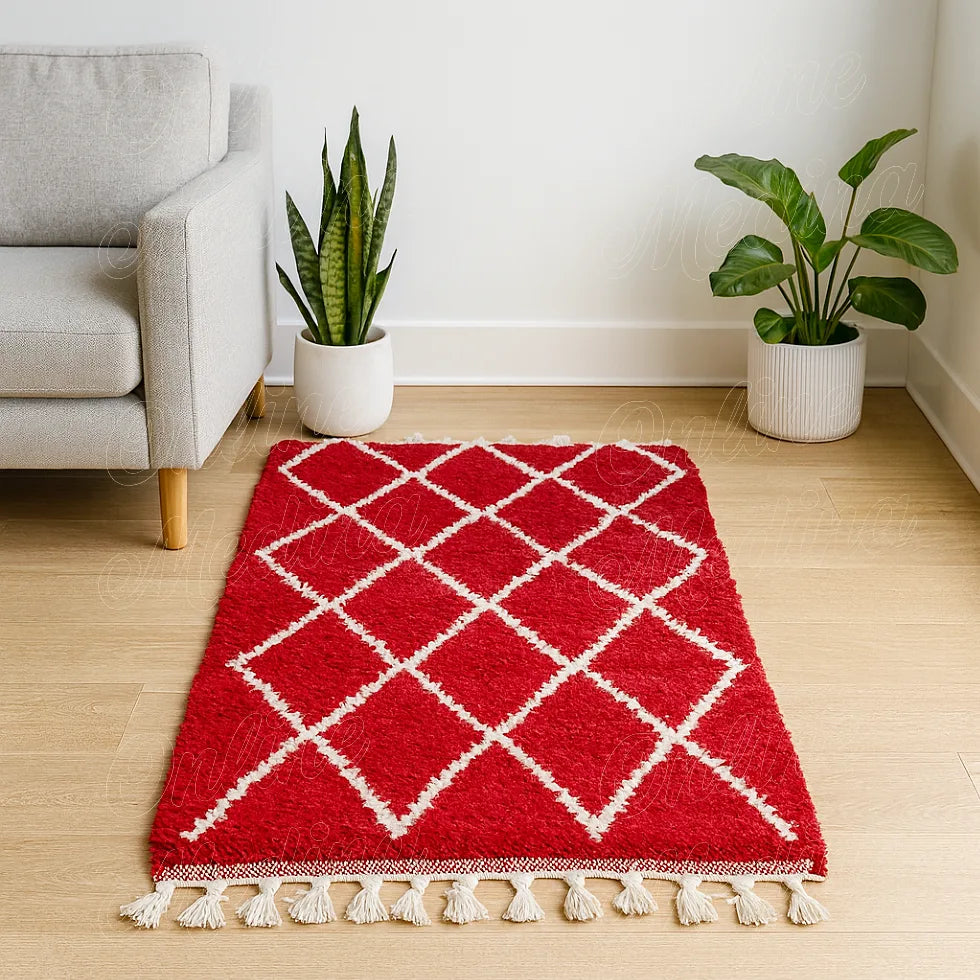 Red Moroccan wool rug with white diamond patterns, handcrafted in Rabat and displayed in a modern living room with a grey sofa and green plants.