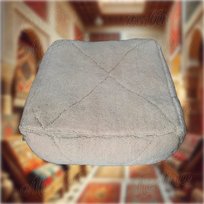 Contemporary Berber pouf in natural beige wool, handmade to bring minimalist elegance to any modern interior.