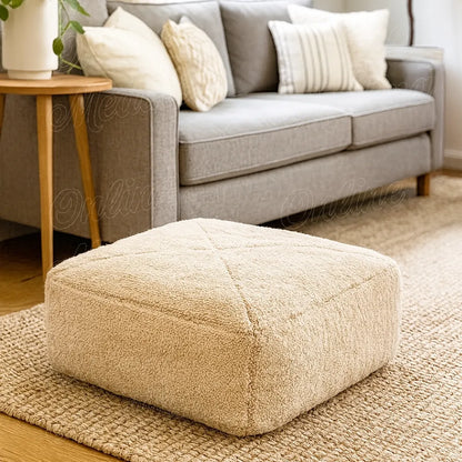 Beige Moroccan wool pouf handcrafted in Rabat, styled in a cozy modern living room with a grey sofa and natural light.