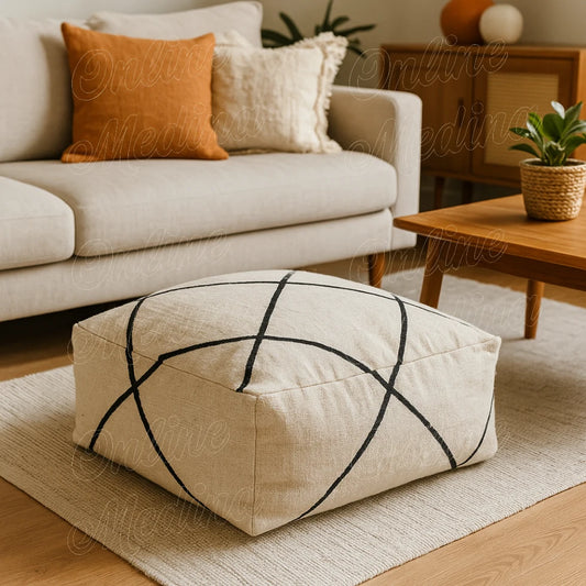 Square Moroccan pouf in natural wool with black diamond pattern, handmade by artisan Omtad in Rabat, placed in a bright living room