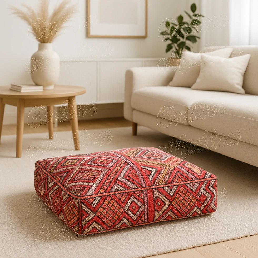 Handwoven Moroccan pouf in red and orange tones with geometric designs