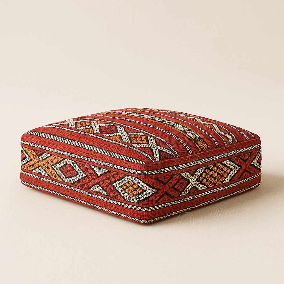 Red Berber Moroccan pouf with geometric motifs on a beige background