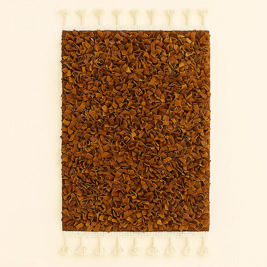 Handwoven brown Moroccan boucharouite rug made from soft recycled leather strips, with white fringes on both ends, photographed on a neutral background.