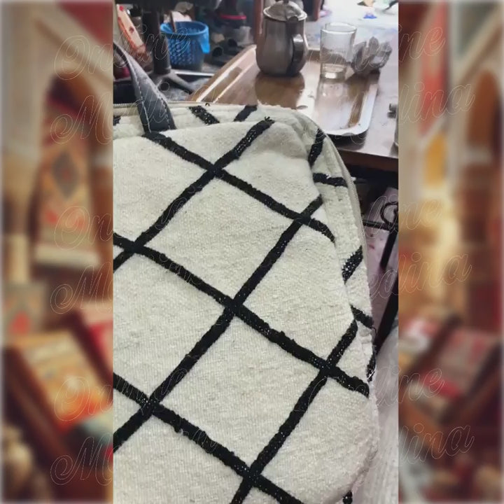 Démonstration de la sacoche pour ordinateur portable 15 pouces, design marocain Beni Ouarain, avec laine tissée et anses en cuir noir, idéale pour un usage quotidien.